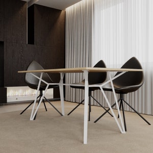 Può includere: Un tavolo da pranzo bianco con un piano in legno e sedie in metallo nero. Il tavolo ha un design geometrico sulle gambe.