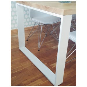 May include: White metal table frame with a wooden top. The table is surrounded by four white chairs with chrome legs.