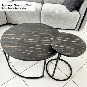 Può includere: Set di due tavolini da caffè ad incastro. I piani Noir Desir Matte presentano un design in marmo nero con venature dorate. Le basi Black Matte hanno un design geometrico moderno. Il testo nell'immagine dice: Piani: Noir Desir Matte, Basi: Black Matte.