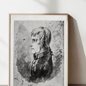 Puede incluir: Un retrato en blanco y negro enmarcado de un hombre de perfil, con el nombre "Bonaparte" y el texto "Profil a la plume de Bonaparte, par Gros" debajo. La obra de arte está en un marco de madera de color claro.