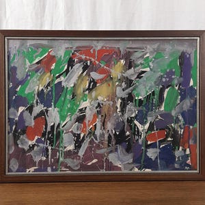 May include: Abstract painting in a dark brown wooden frame. The artwork features a vibrant mix of colors, including red, green, purple, and yellow, with white and gray brushstrokes. The painting has a textured appearance.