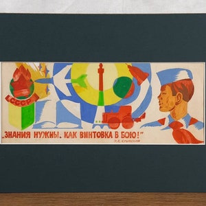 Può includere: Una stampa rettangolare in un passe-partout scuro con una colorata illustrazione di propaganda sovietica. Raffigura una giovane persona in uniforme blu con un fazzoletto rosso, un trattore, un libro e il testo in cirillico: "ЗНАНИЯ НУЖНЫ. КАК ВИНТОВКА В БОЮ!"