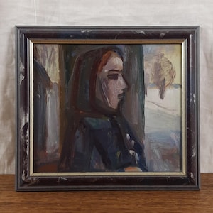 May include: Oil painting of a woman in profile, wearing a dark head covering and coat. The artwork is framed in a dark brown, slightly distressed wooden frame. The background suggests a winter landscape with a tree.