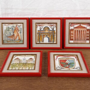 May include: Five framed watercolor paintings with red wooden frames. The paintings depict architectural scenes and a sailboat. The artwork is set against a neutral linen-textured background.