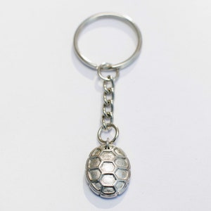Op de afbeelding: Zilveren sleutelhanger met een voetbalbedel. De bedel is versierd met een zeshoekig patroon.