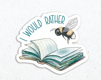May include: A white sticker with a watercolor illustration of an open book and a bumblebee flying above it. The text "I would rather" is written in teal around the book. The artist's name and website are printed in black at the bottom of the sticker.