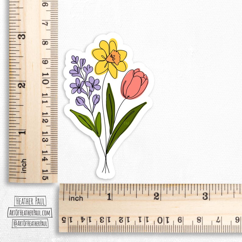 sticker featuring a purple freesia, a yellow daffodil with and orange center and a  pinkish-red tulip over a white background with brown rulers to show sizing