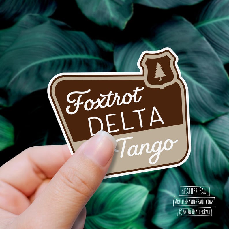 sticker featuring a national parks style sign with the text reading the phrase foxtrot delta tango over a background with green leaves