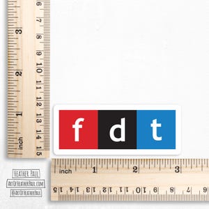 sticker featuring parody of the NPR logo with the letters fdt over a white background with brown rulers to show sizing