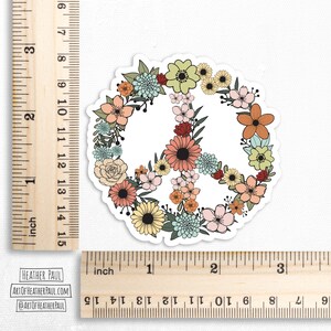 May include: A peace sign sticker with a floral design. The peace sign is outlined in black and filled with a variety of flowers in shades of pink, yellow, orange, blue, and green.