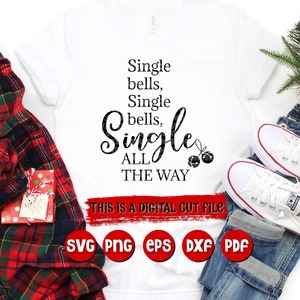 May include: White t-shirt with the text "Single bells, Single bells, ALL THE WAY" in black. The text is in a festive font with a Christmas bell graphic. The text "THIS IS A DIGITAL CUT FILE" is below the main text.  The t-shirt is displayed on a white background with a red and black plaid shirt, blue jeans, and white sneakers.