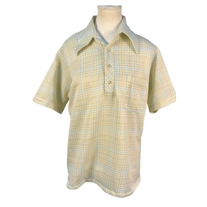 May include: A short-sleeved, button-down shirt in a plaid pattern of yellow and light blue. The shirt has a chest pocket and a wide collar. The fabric appears to be a lightweight woven material, suitable for warmer weather.