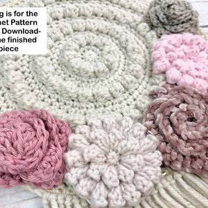 Puede incluir: Patr&oacute;n de crochet para un tapiz de pared con una base circular y varias flores de crochet en tonos rosa, beige y gris.