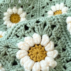 Daisy granny square blanket with a green background, white petals, and a yellow center. The listing is for a digital download crochet pattern and not the finished blanket.