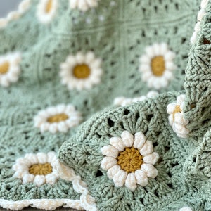 Daisy granny square blanket with a green background, white petals, and a yellow center. The listing is for a digital download crochet pattern and not the finished blanket.