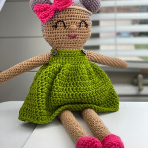 Crochet doll wearing a green dress, pink shoes and purple hair. Listing is for a crochet doll pattern and not the finished piece.