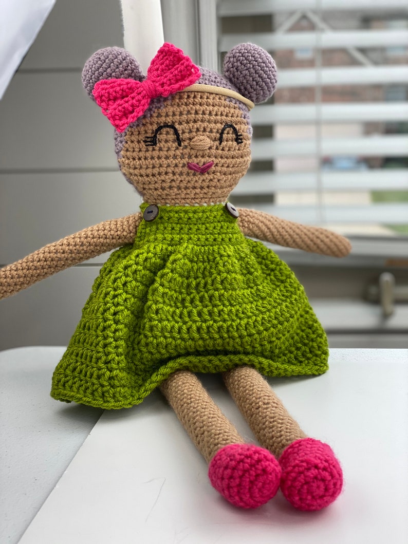 Crochet doll wearing a green dress, pink shoes and purple hair. Listing is for a crochet doll pattern and not the finished piece.