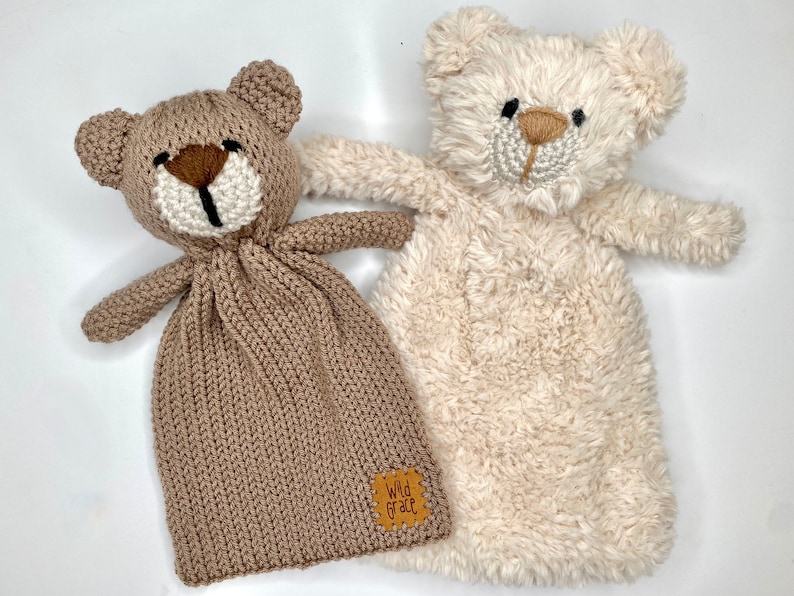 以下が含まれることがあります： 2つのぬいぐるみテディベアセキュリティブランケット。1つは茶色でニットで白い顔、もう1つは白くてふわふわで茶色の顔をしています。どちらも黒い目と茶色の鼻をしています。茶色のクマには「Wild Grace」と書かれた茶色の革タグが付いています。