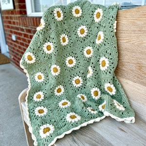 Daisy granny square blanket with a green background, white petals, and a yellow center. The listing is for a digital download crochet pattern and not the finished blanket.