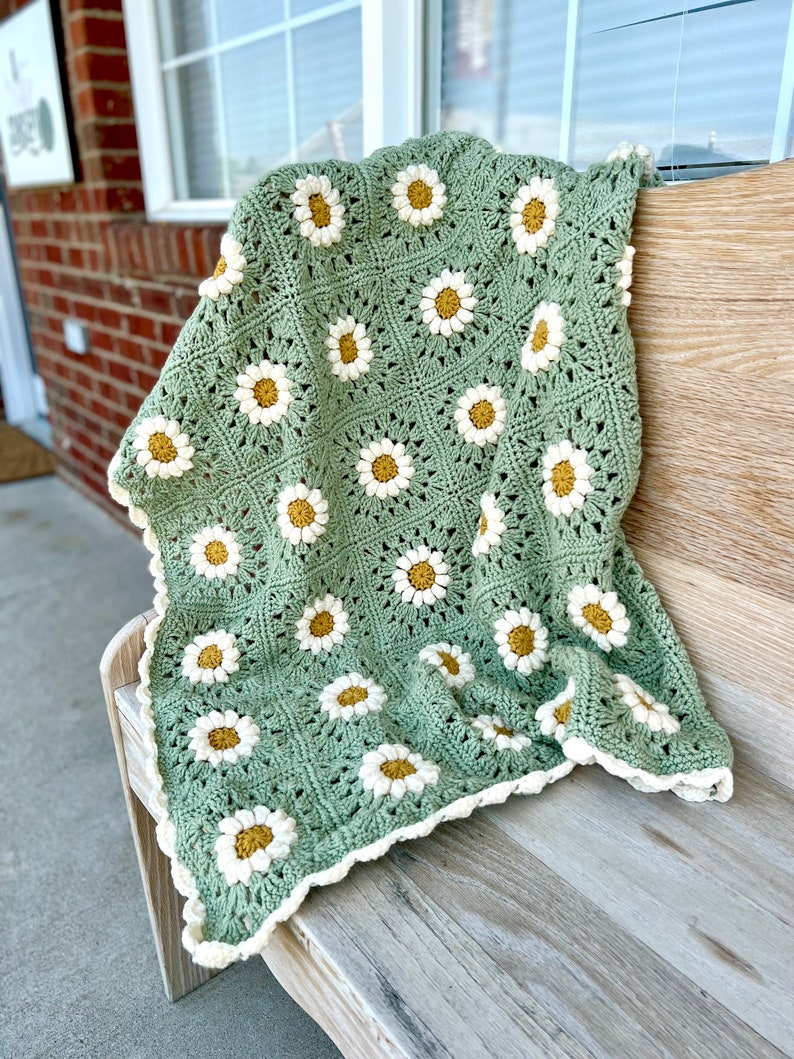 Daisy granny square blanket with a green background, white petals, and a yellow center. The listing is for a digital download crochet pattern and not the finished blanket.
