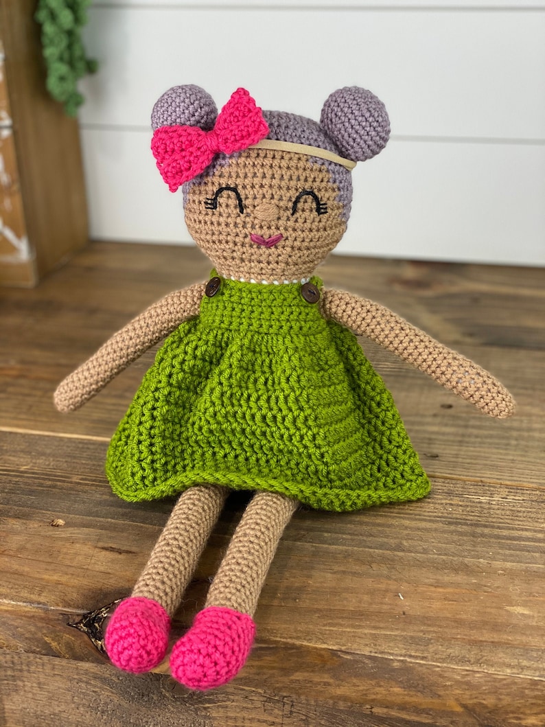 Crochet doll wearing a green dress, pink shoes and purple hair. Listing is for a crochet doll pattern and not the finished piece.