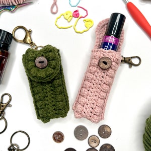 May include: Two crocheted pouches with buttons, one green and one pink. The green pouch has a key ring and a small bottle of essential oil labeled "doTERRA Clary Sage".
