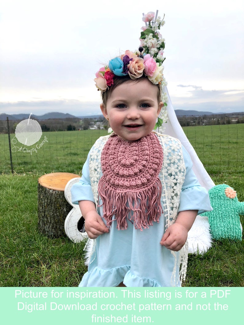 Caucasian baby girl wearing a rosy pink crochet baby bib, a blue shirt and a flower crown.  Listing is for a crochet bib pattern and not the finished baby bib.