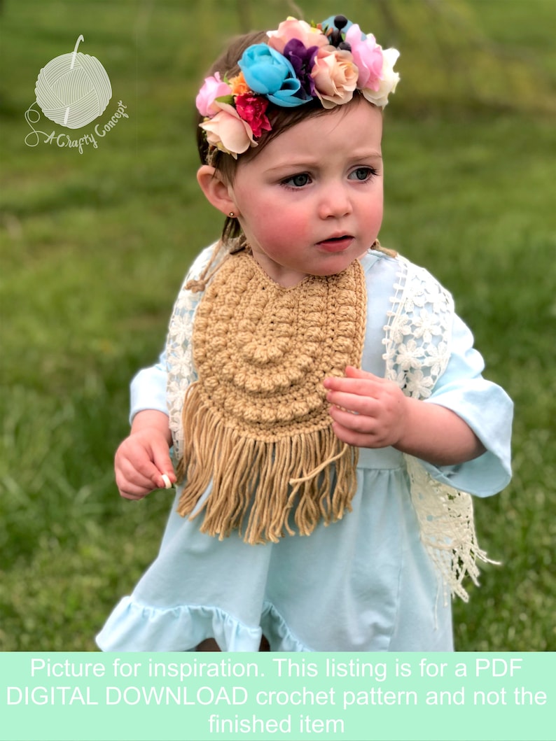 Caucasian baby girl wearing a dark tan crochet baby bib, a blue shirt and a flower crown.  Listing is for a crochet bib pattern and not the finished baby bib.