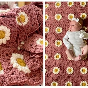 May include: A pink crocheted baby blanket with white and yellow daisy flowers. The blanket is laid out flat with a baby lying on top of it.