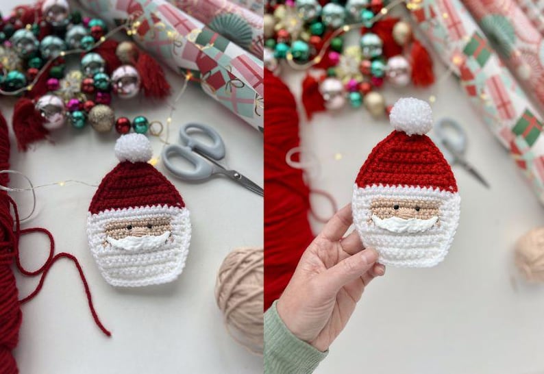 May include: A crocheted Santa Claus ornament with a red hat, white beard, and black eyes. The ornament is held in a hand against a white background.