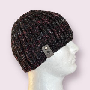 May include: A black, gray, and burgundy knit beanie with a leather tag that says "Pretty Knot".