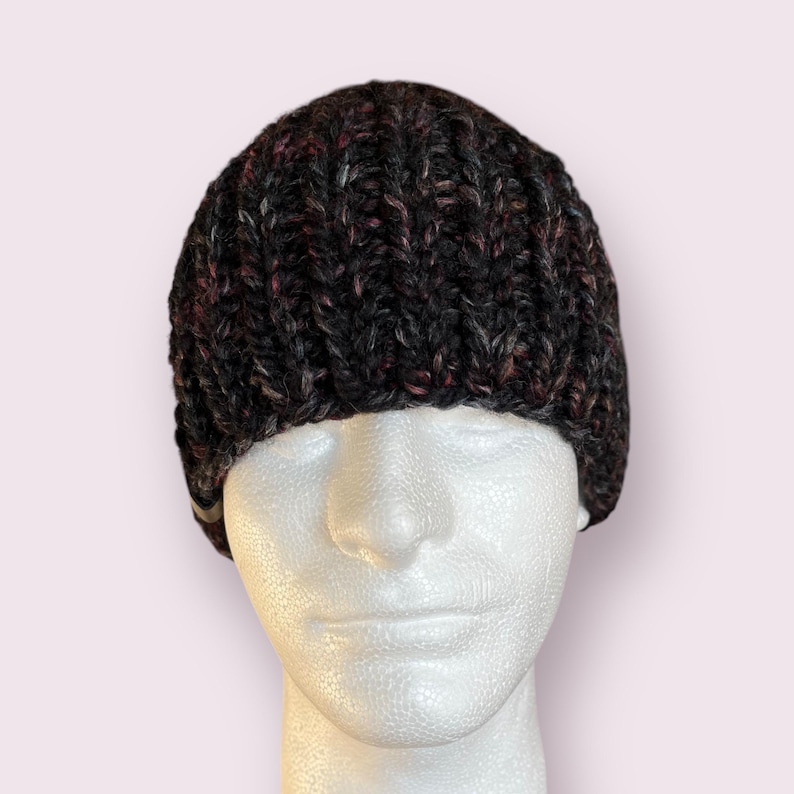 May include: A black, gray, and pink knit beanie hat. The hat is on a white mannequin head.