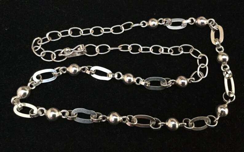 May include: A silver chain necklace with oval links and round beads.