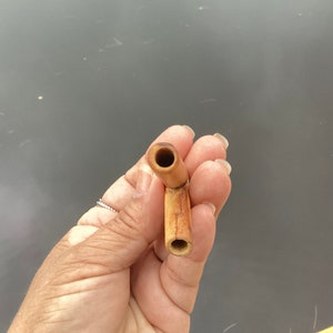 May include: A wooden pipe with a brown and natural finish. The pipe has a curved stem and a round bowl.