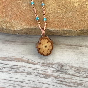 May include: A copper chain necklace with turquoise beads and a wooden flower pendant.