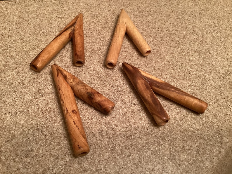 May include: Four wooden Y-shaped objects with a smooth, polished finish. The objects are made of light brown wood with darker brown streaks.