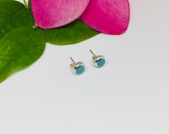 May include: A pair of silver stud earrings with small, round turquoise stones.