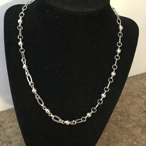 May include: A silver chain necklace with alternating round beads and oval links.