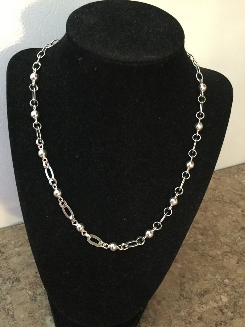 May include: A silver chain necklace with alternating round beads and oval links.