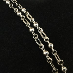 May include: A silver chain necklace with round beads. The chain is double-stranded and has a delicate, feminine look.