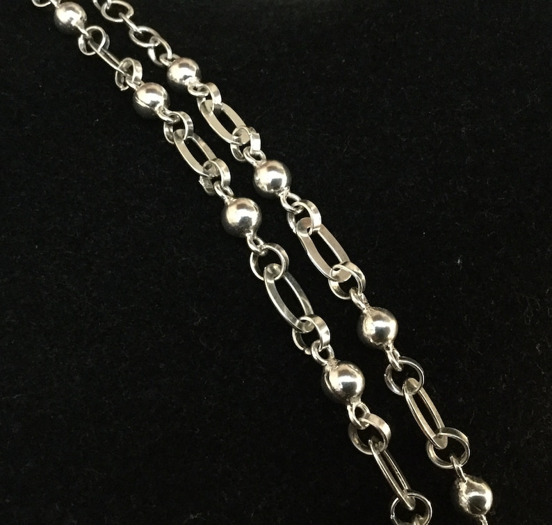 May include: A silver chain necklace with round beads. The chain is double-stranded and has a delicate, feminine look.