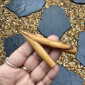 May include: A wooden smoking pipe with a Y-shaped design. The pipe is made of light brown wood and has a smooth finish.