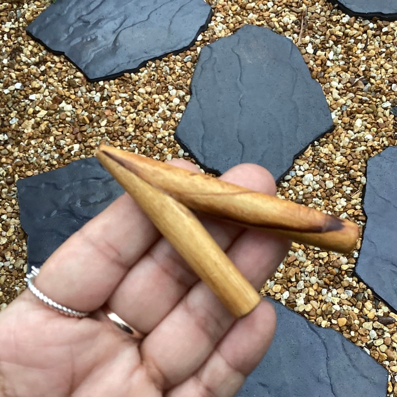 May include: A wooden smoking pipe with a Y-shaped design. The pipe is made of light brown wood and has a smooth finish.