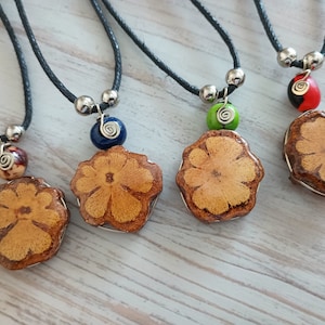 May include: Four necklaces with wooden flower pendants and colorful beads. The necklaces are made with black cord and silver metal accents.