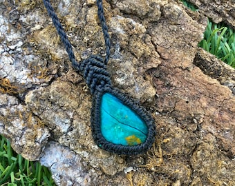 May include: A turquoise gemstone pendant with black macrame cord. The pendant is teardrop shaped and has a natural, organic look.