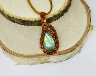 May include: A teardrop-shaped labradorite gemstone pendant wrapped in copper wire, hanging from a brown leather cord.