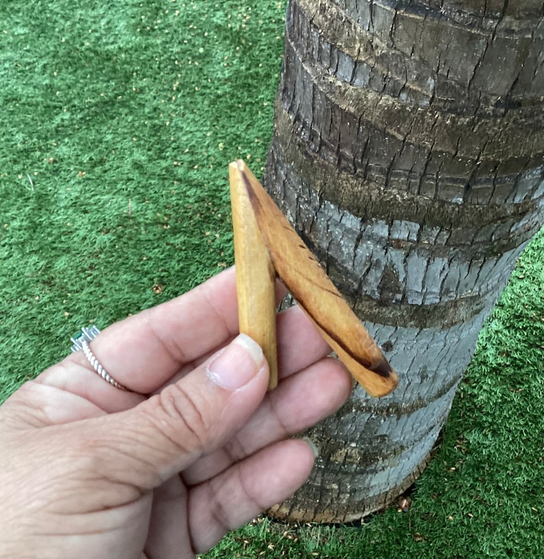 May include: A wooden carving in the shape of a letter A, with a light brown color and a darker brown grain pattern.