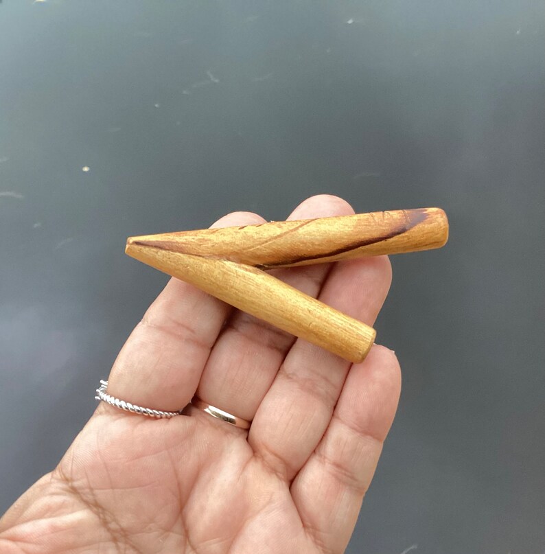 May include: A wooden smoking pipe with a Y-shaped design. The pipe is made of light brown wood with darker brown streaks.