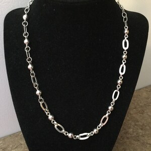 May include: A silver chain necklace with round beads and oval links.