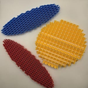 May include: Three colorful plastic mesh shapes: a blue diamond, a yellow circle, and a red diamond. The mesh is made of thin, intersecting lines, creating a grid-like pattern. The shapes are arranged on a white surface.